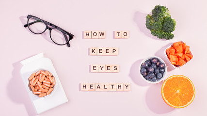 Essential vitamins and supplements to keep eyes healthy on pink background. Eyeglasses, vitamin...