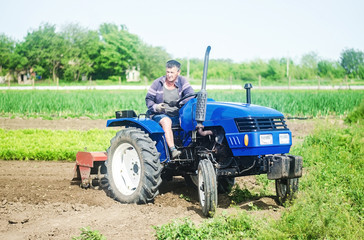 A farmer drives a tractor on a farm field. Agricultural cultivation technology equipment and technical transport. Loosening the surface, cultivating land for further planting. Farmer support subsidies
