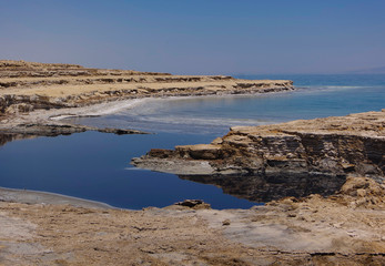 The coast of the dead sea against the backdrop of the mountains and the blue sky. 