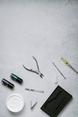 Bottles of nail polish, manicure tools and hand cream on grey concrete table top flat lay. How to do manicure at home concept. Do manicure by yourself while staying at home, top view