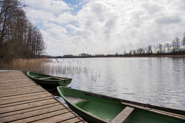 Obraz premium Old boat on lake. Cloudy Spring Day.