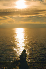 woman sitting at sea beach enjoying the beauty of sunset
