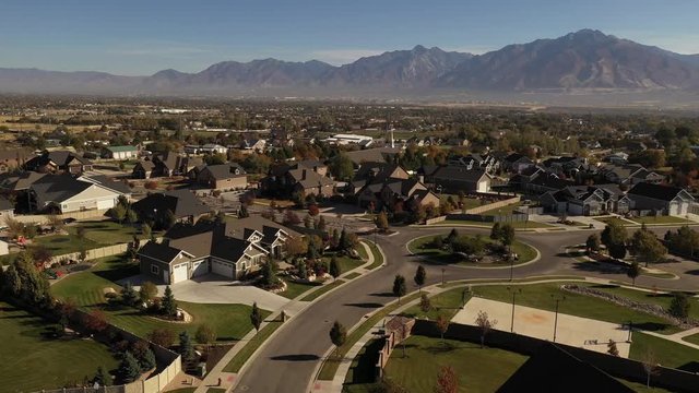 Aerial shot with upper class suburban neighborhood in valley with mountains