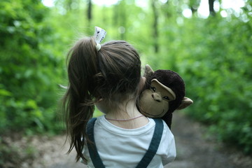 Little girl walking with her toy.  Child alone in the forest. Offended girl.Тhe little girl was lost alone in the forest. Little girl with her toy alone in the forest.Unattended child