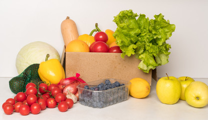 groceries box with vegetables and fruits on white kitchen background. Food delivery services during coronavirus pandemic and social distancing. Shopping online.