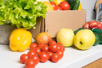 groceries box with vegetables and fruits on white kitchen background. Food delivery services during coronavirus pandemic and social distancing. Shopping online.