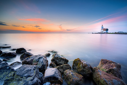 Lighthouse on the Dutch coast near the island of 'marken' during sunrise on a large inland lake