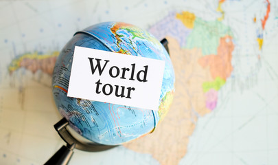 World tour - text on a white sheet with Globe on the background of the atlas map