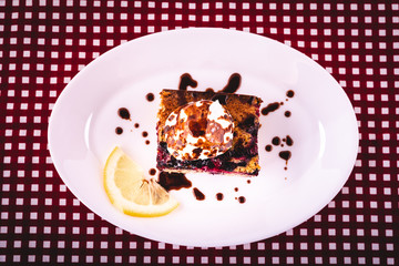 Homemade cake with forest fruit served on a plate with a glass of refreshing lemonade with lemon slice