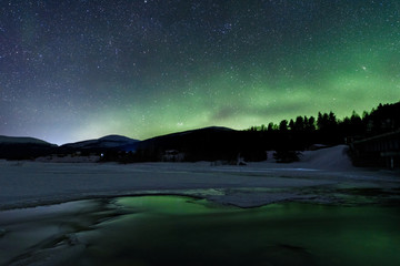 Alluvial stars in the night sky over the Kola Peninsula in the light of the Polar Lights on the banks of the Kolvitsa River. Russia, Murmansk region