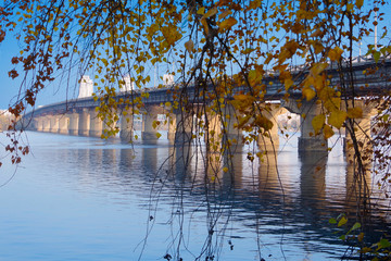View of the bridge of the Potona through autumn foliage. 