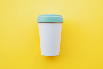 Reusable stylish eco-friendly bamboo cup for take away coffee on yellow background.