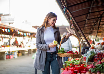 Woman holding a basket and buying vegetables