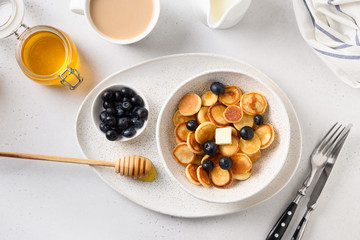 Homemade tiny pancake with blueberry and strawberry on white table. View from above. Copy space. Trendy breakfast.