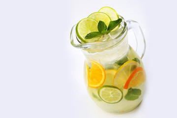 Orange and lime lemonade with mint in a tall glass jug on a white background. An isolated object. Copy space.