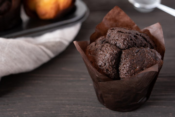 Homemade Chocolate Muffin. Dark wooden background, cupcake shape and light linen textile. Copy space. The concept of home baking. Close up.