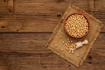 Dry chickpea in ceramic bowl on old wooden boards background. Traditional ingredient for cooking hummus