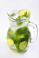 Lemonade made from cucumber slices and green Basil in a tall glass jug on a white background. Vertical photo. An isolated object. Top view.