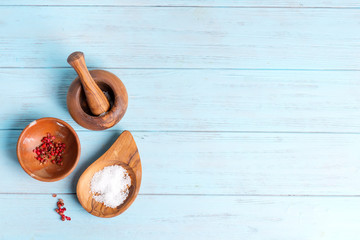 Top view set from wooden bowls with natural salt and condiments on a light blue wooden background. Top view.