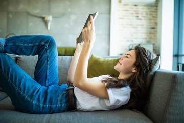 Young happy woman read book on sofa in living room