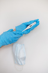 Medic's hand wearing a blue latex glove holding a thermometer