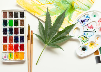 Set of watercolor paints, art brushes, palette and blank album. Marijuana leaf. Cannabis reveals...
