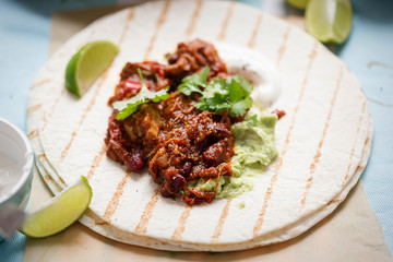 Slow cooked chipotle chicken on tortilla with guacamole and sour cream
