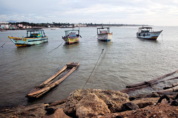 Kanniyakumari, India - September 14, 2013: A bamboo raft, and fishing boats tied along the shore.