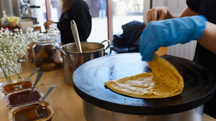 prepares pancakes on a stove with jam flips over with a wooden shelf