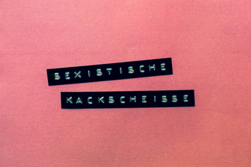 Ein rosa Hintergrund auf dem auf Deutsch die Worte sexistische Kackscheiße geschrieben stehen. ...