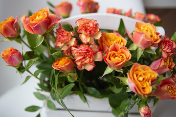 Bright red-orange rose, delicate bouquet in a white wooden basket