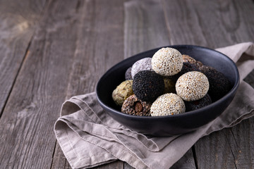 Raw energy bites balls prepared with natural ingredients on old rustic wooden background