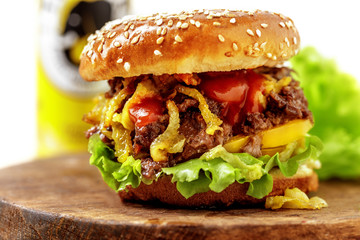 Fresh homemade burger with salad, beef, onions and pepper and a can of beer on a wooden board. On white background
