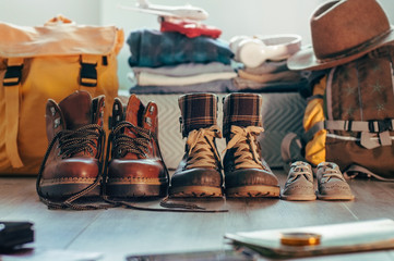 Family hiking shoes standing in a row near backpacks and things indoor