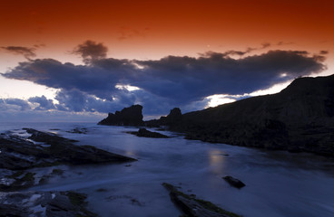 Red sky and rocky sunrise seascape.