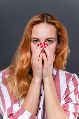 Young pretty woman covers her face with hands with painted red nails