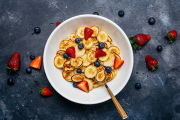 Tiny pancakes for breakfast. Pancakes with strawberries and blueberries cooked in the morning for breakfast in the home kitchen. Food Background.