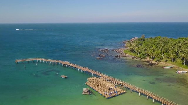 Aerial view of bridge and a cottage made out of bambbo in a tropical resort. Bamboo bridge over the blue sea with bambbo cottage in a resort in Asia.