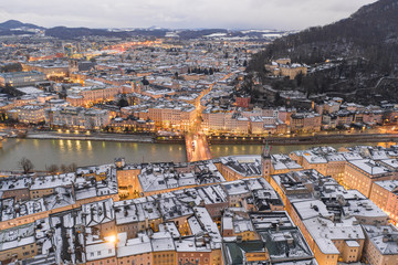 Aerial drone view of Salzburg state bridge and city skyline covered with snow at dusk time