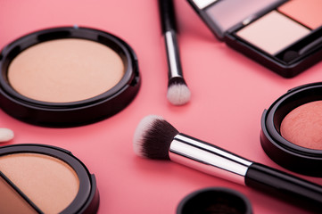 Cosmetic palette and face shadow with brushes lies on a pink background