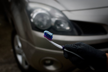 Technician with holding toothbrush and toothpaste to shine and brighten the headlights of the car....