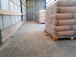 Unloading bags of cement from a truck with a forklift.