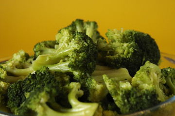 green boiled broccoli on the yellow background, close up shot