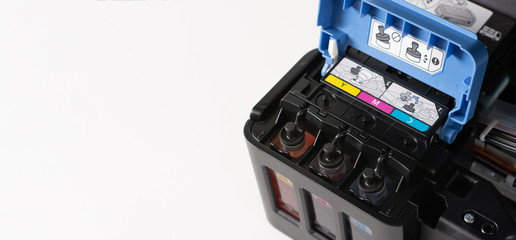Up close, ink tanks from a printer displaying CMYK Cyan, Magenta, Yellow and Key colors, continuous...
