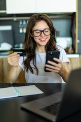 Young woman using laptop and mobile phone to online shopping and pay by credit card.