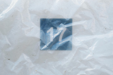 Obraz premium Number Seventeen on stadium seat under the plastic bag. Numbers tell the seats of those who came to watch sports. Empty white plastic seats in a stadium. Matches to be played without fans.