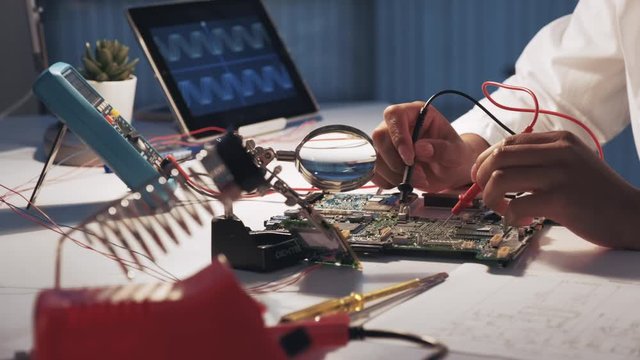 View of woman's hands testing electronic board in laboratory using multimeter tester and other technologies