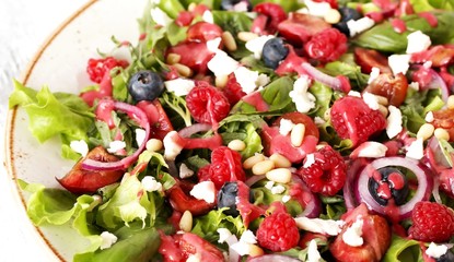 Salad with berries-raspberry, blueberry, sweet cherry, red onion, feta cheese, pine nuts . Dressed with raspberry vinaigrette. Soft focus.