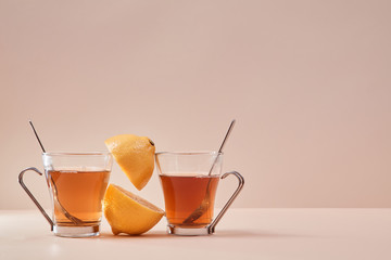 Glass cup with fruit tea. Copy space for advertisement. Two part of juicy lemon on pink background. English tea concept