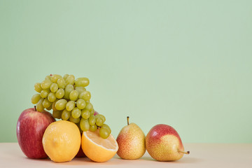 Ripe lemon apple and pear. Mellow bunch of grapes. Summer fruit. Diet food. Healthy. Copy space. Green background